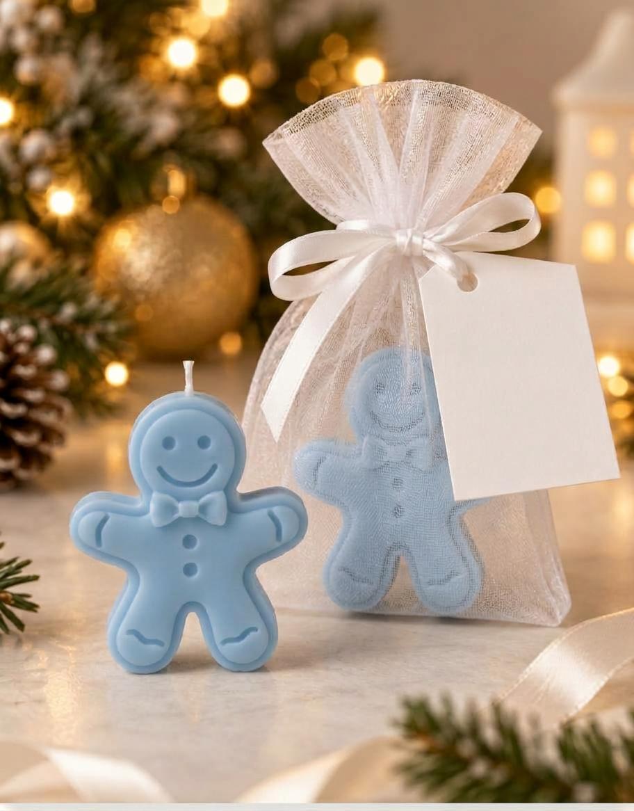 Vela artesanal em forma de boneco de gengibre azul com sorriso e gravata-borboleta, em saquinho de organza branco