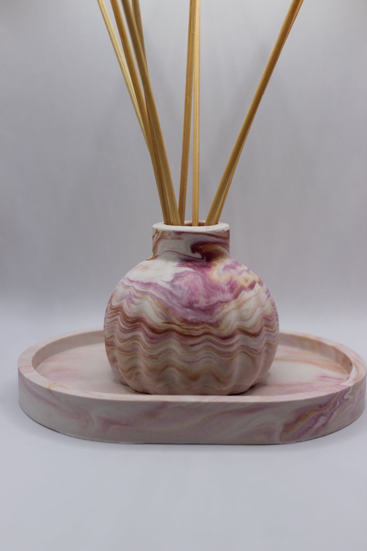 Conjunto Aura — difusor com varetas sobre tabuleiro de gesso marmorizado rosa