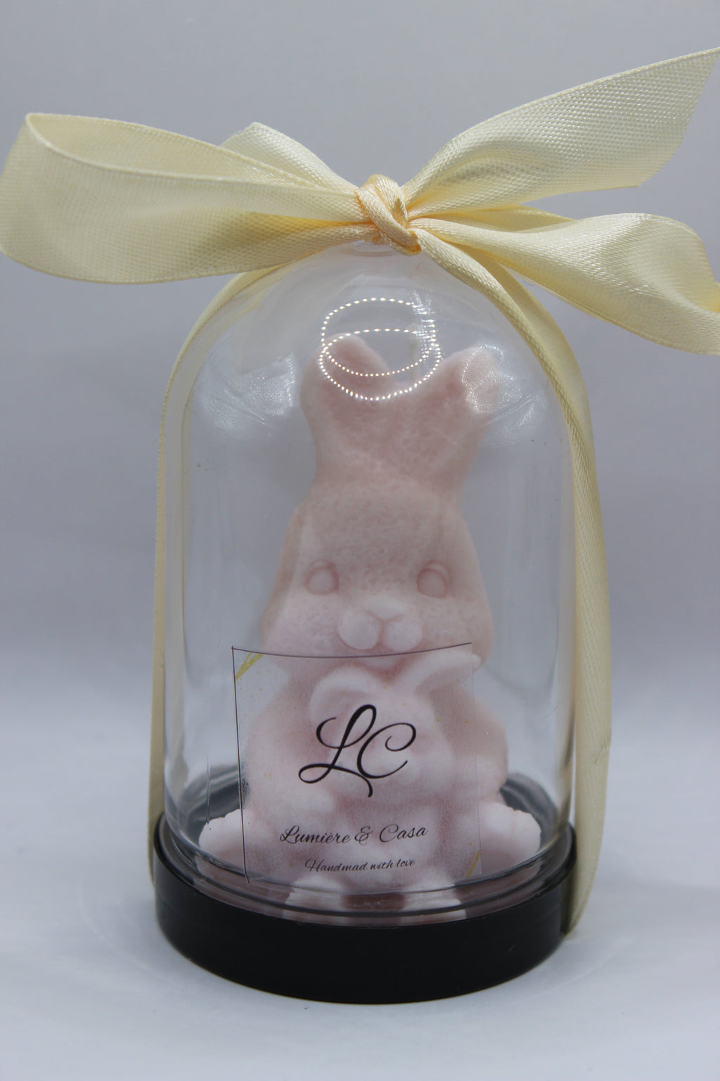 Bunny Hug – vela artesanal coelhinho rosa pastel em redoma de vidro com laço creme