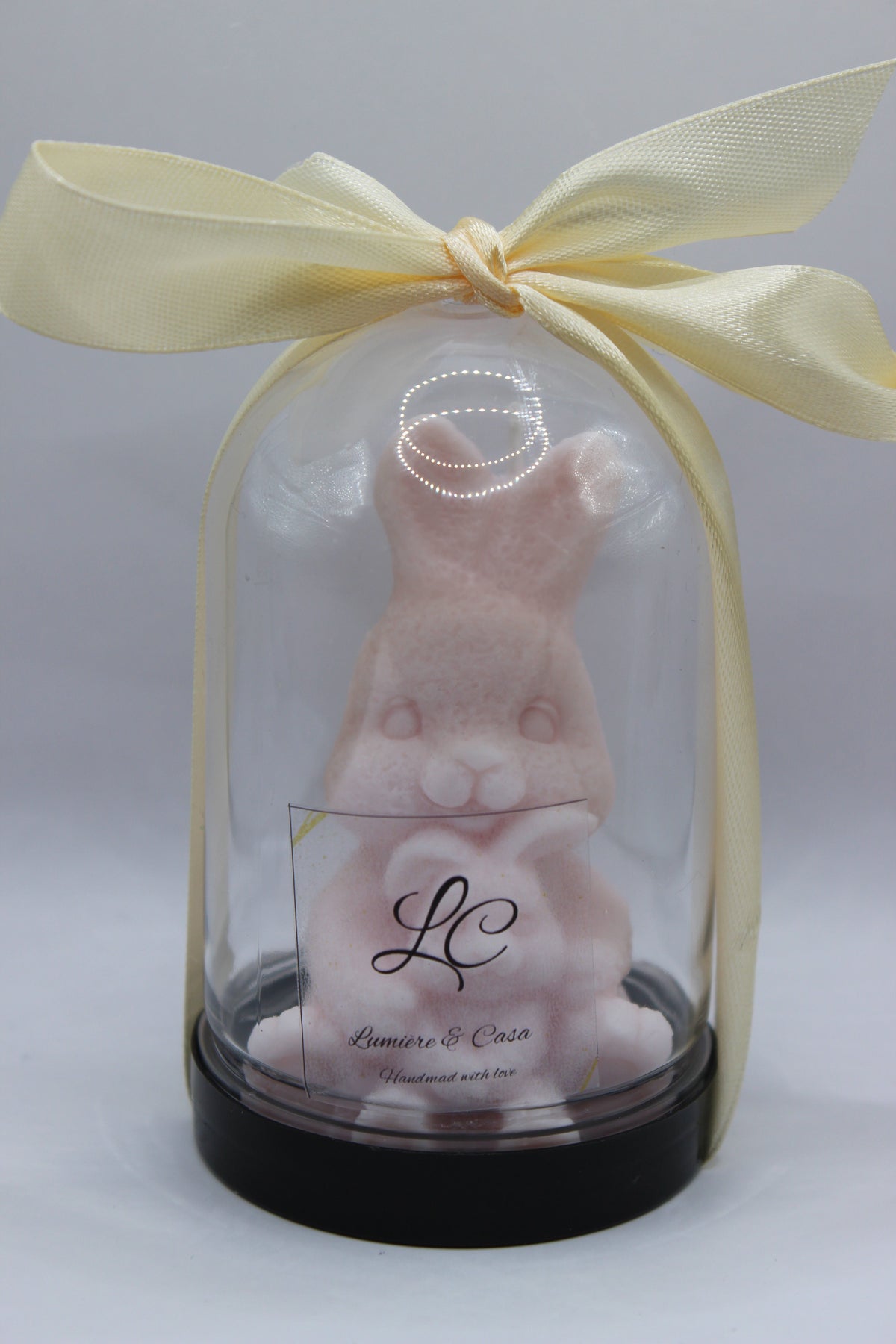 Bunny Hug – vela artesanal coelhinho rosa pastel em redoma de vidro com laço creme