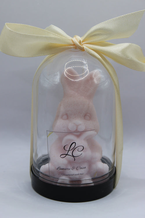 Bunny Hug – vela artesanal coelhinho rosa pastel em redoma de vidro com laço creme